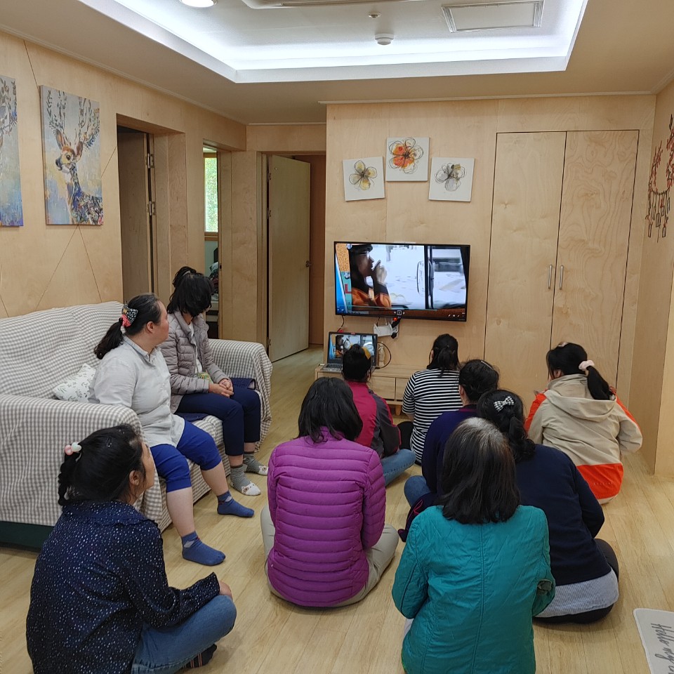 여러명의 장애가족들이 티비앞에서 함께 온라인으로 소방교육을 받고 있다