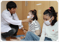 남자 의사선생님이 장애아동을 치료하고 있는 사진. 귀에 무엇인가를 대고 있다