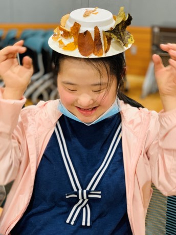 접시에 낙엽을 붙여 만든 모자를 쓰고 즐거워하는 장애아동