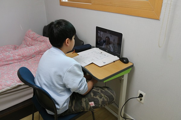 새학기를 맞이하여 방안에서 zoom을 이용해 수업에 참여하고있는 남자 장애아동