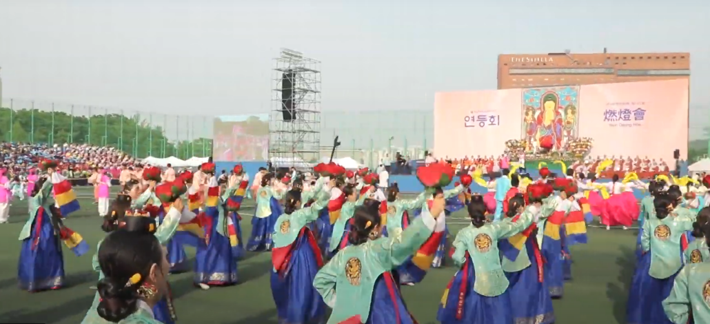 유튜브 연등회 채널에서 발췌한 지난 동국대학교 운동장에서 진행된 연등축제 모습. 전통 한복을 입은 다수의 사람들이 연꽃등을 들고 공연을 펼치고 있다.