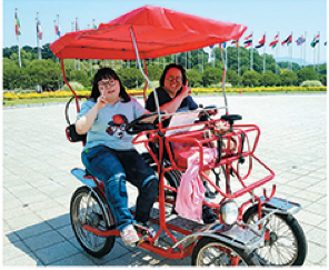 2명의 장애가족이 2인용 자전거를 나란히 앉아있는 모습