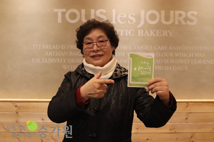 나눔이어달리기 리플렛을 손으로 가리키고 있는 박정옥 후원가족님의 모습. 장액족행복지킴이승가원ci