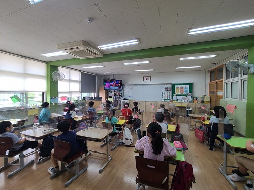  원효초등학교 아이들이 각자의 책상에 앉아 장애바로알기 교육 영상을 시청하고 있는 사진./책상에는 비말방지용 가림막이 설치되어 있다.