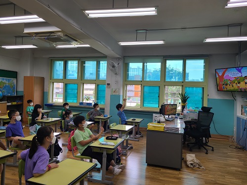  원효초등학교 아이들이 마스크를 쓰고 교실 앞의 모니터로 장애바로알기 교육 영상을 시청하고 있는 사진./모니터 하단에는 선생님 책상이 있다.
