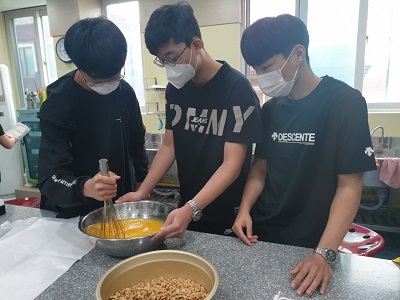 세명의 참여자가 모여 요리활동을 하고 있는 모습. 계란물을 거품기로 젓고 있다.