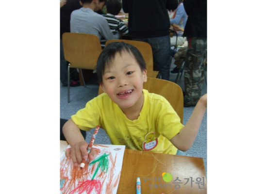 김효섭 장애아동의 어릴적 사진. 화면을 보고 브이를 하고 있다. 장애가족행복지킴이 승가원 CI