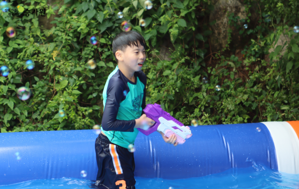 간의 수영장에서 보라색 물총을 들고 물놀이를 하는 남자아이 사진 / 왼쪽 상담에 장애가족 행복지킴이 승가원ci