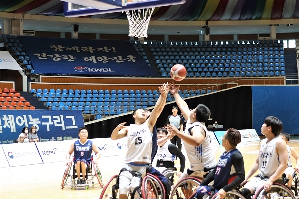 휠체어농구경기모습. 두명의 제주팀 선수가 공에 손을 뻗고 있고 다른 선수들이 집중하고 있다