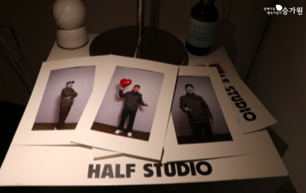 오른쪽 상단 장애가족 행복지킴이 승가원ci / 흰색 종이 프레인안에 팔짱을끼고, 빨간 풍선을 들고, 정면을 바라보면 찍은 사진 / 하단에 HALF STUDIO