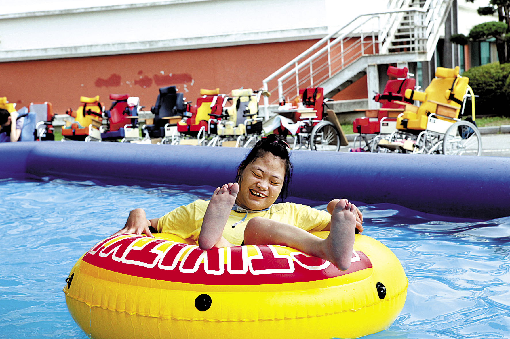 승가원 여름통합캠프에서 노란색 튜브를 타고 에어바운스에서 물놀이를 즐기고 있다. 얼굴에는 웃음이 가득한 모습이다.