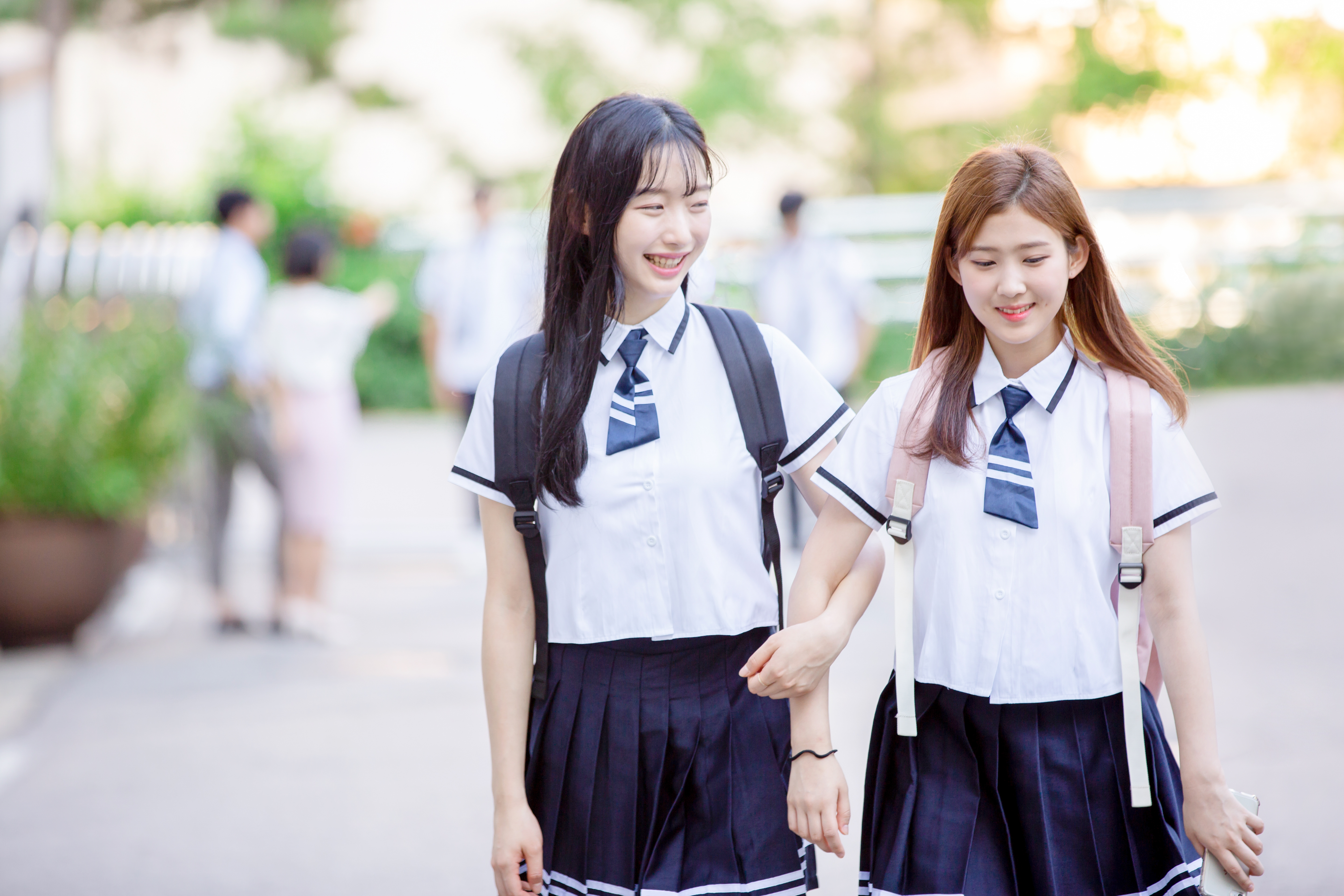 두 여학생이 밝은 표정으로 학교를 향하고 있는 이미지 사진