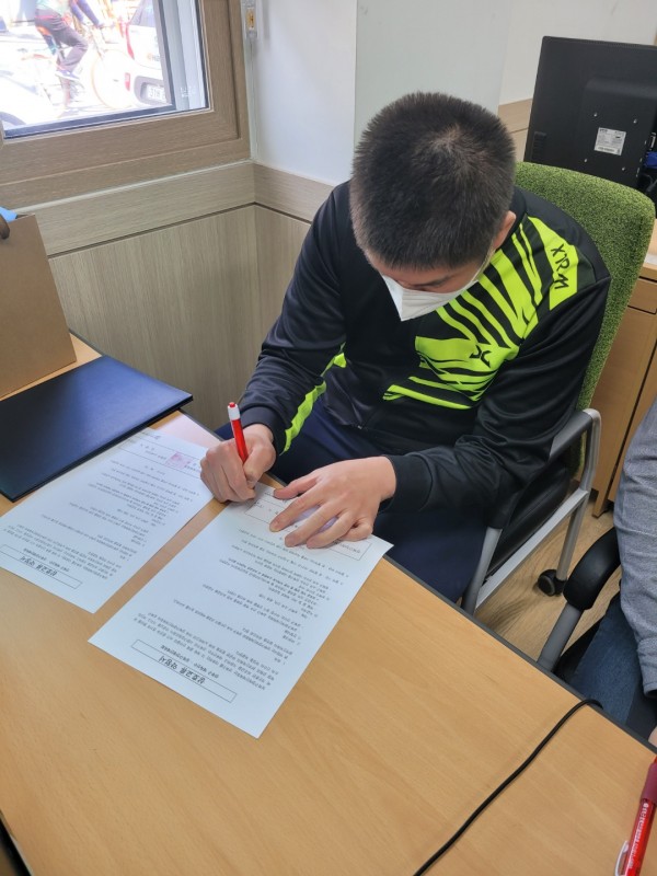 약정서(협약서)에 서명을 하고 있는 김형식 선수의 모습. 빨간색 볼펜을 들고 서명하고 있다