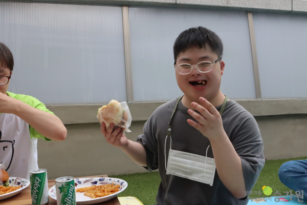 CI 삽입 장애가족 행복지킴이 승가원, 한 손에 햄버거를 들고 환하게 웃으며 맛있게 먹는 장애아동의 모습