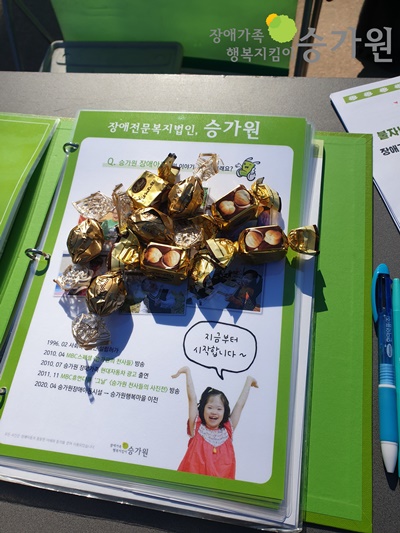 승가원 책자에 많은 초콜릿이 놓여있는 사진/ 오른쪽 상단에 장애가족 행복지킴이 승가원 ci 삽입