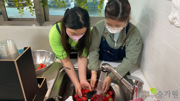 두명의 장애가족이 깨끗하게 딸기를 씻는 모습. 장애가족행복지킴이 승가원 CI
