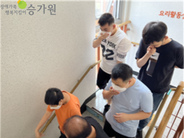  5명의 장애가족이 대피실습에 참여하는 모습. 모두 손으로 입을 막고 계단을 타고 내려가고 있다. 좌측 상단 '장애가족행복지킴이승가원' CI