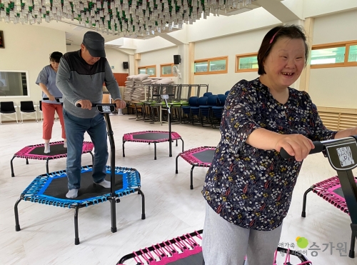 개별 건강관리 및 비만관리 프로그램 중 뛰놀다 프로그램으로 두 명의 장애가족이 트램폴린위에서 밝게 웃고 있는 모습 장애가족행복지킴이 승가원 ci 로고 삽