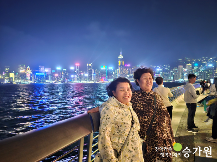 저녁에 홍콩 바다 앞에 있는 장애가족 두 명의 사진. 오른쪽 아래 승가원 ci삽입