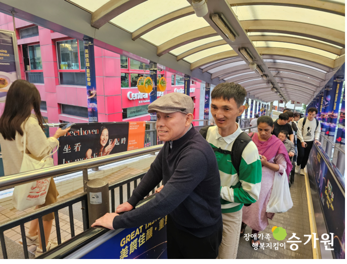 홍콩 미드레벨 에스컬레이터에 있는 장애가족 두 명의 사진. 오른쪽 아래 승가원 ci삽입